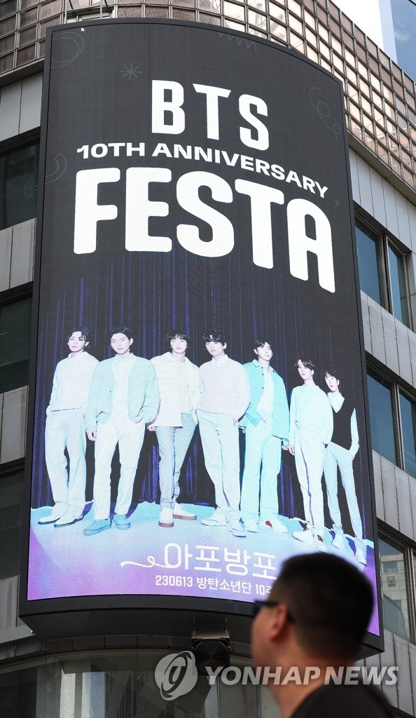 Un turista mira un cartel sobre el décimo aniversario de BTS, el 12 de junio de 2023, en Seúl, mientras se lleva a cabo un festival, de dos semanas de duración, para celebrar el hito.